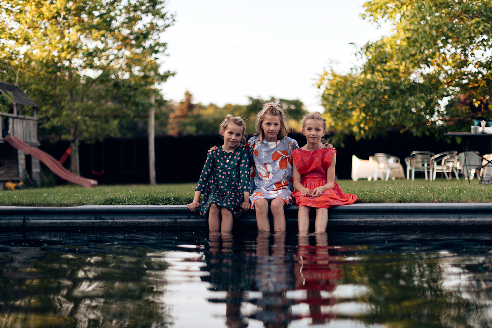 Young,Little,Sisters,Having,Fun,Sitting,At,Pool,Side,Outdoor