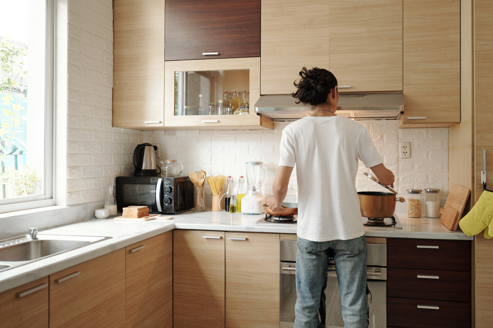 Young,Man,In,Jeans,And,White,Shirt,Cooking,Dinner,At