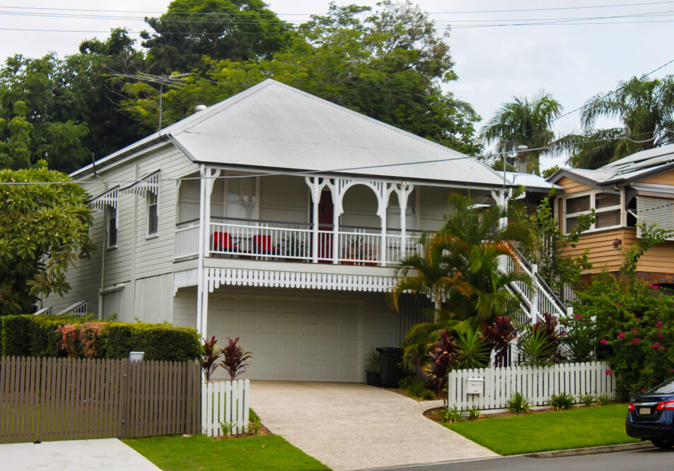 White,Queenslander,Home,With,Tropical,Greenery,And,Tall,Trees,On