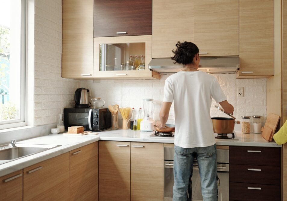 Young,Man,In,Jeans,And,White,Shirt,Cooking,Dinner,At